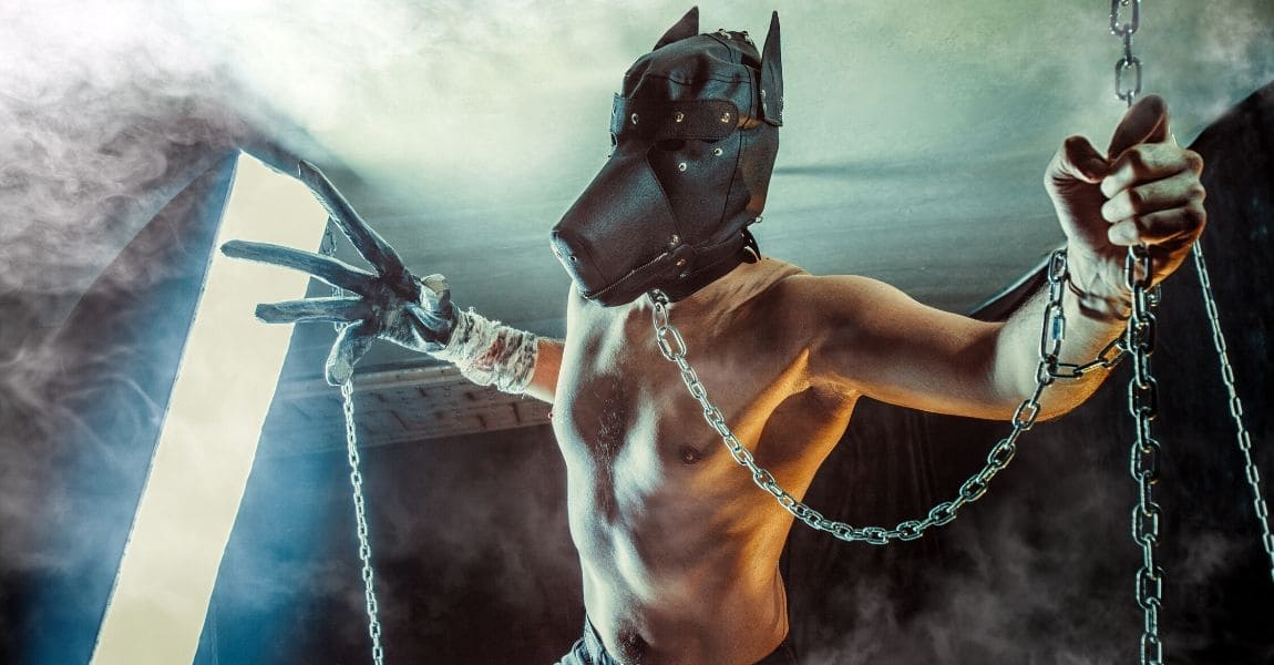 Người mặc hood chó, đeo bao tay có móng vuốt chuẩn bị tấn công, tay kia đang nắm dây xích