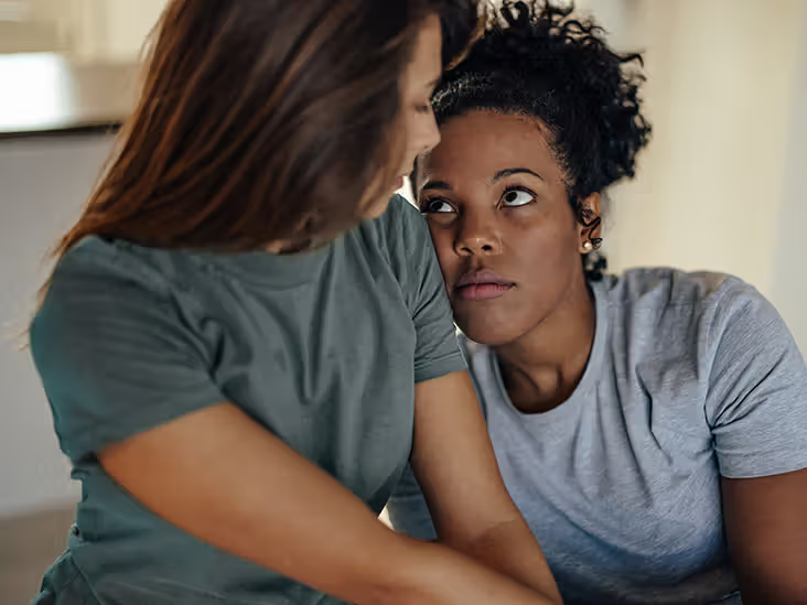 Một người nữ đang tựa đầu vào vai người nữ khác