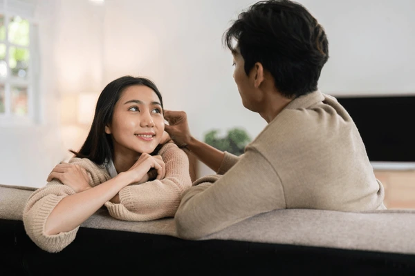 Người nam đang vuốt tóc người nữ khi người nữ đang nhìn người nam cười